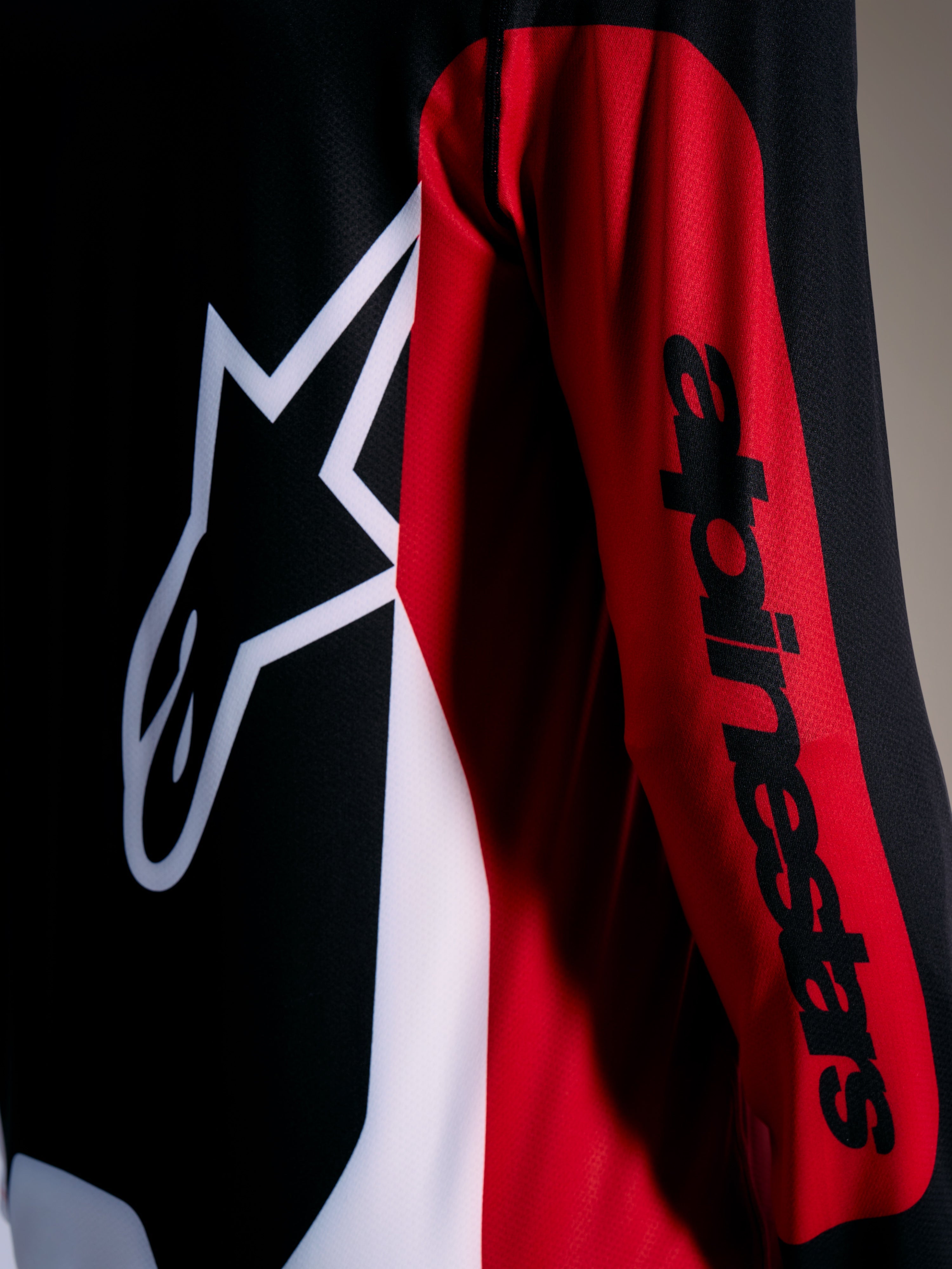 Röd Alpinestars A-Dura Race-tröja med vit Astars-logotyp och svart ordmärke på ärmen, MTB-plagg för hög prestanda.