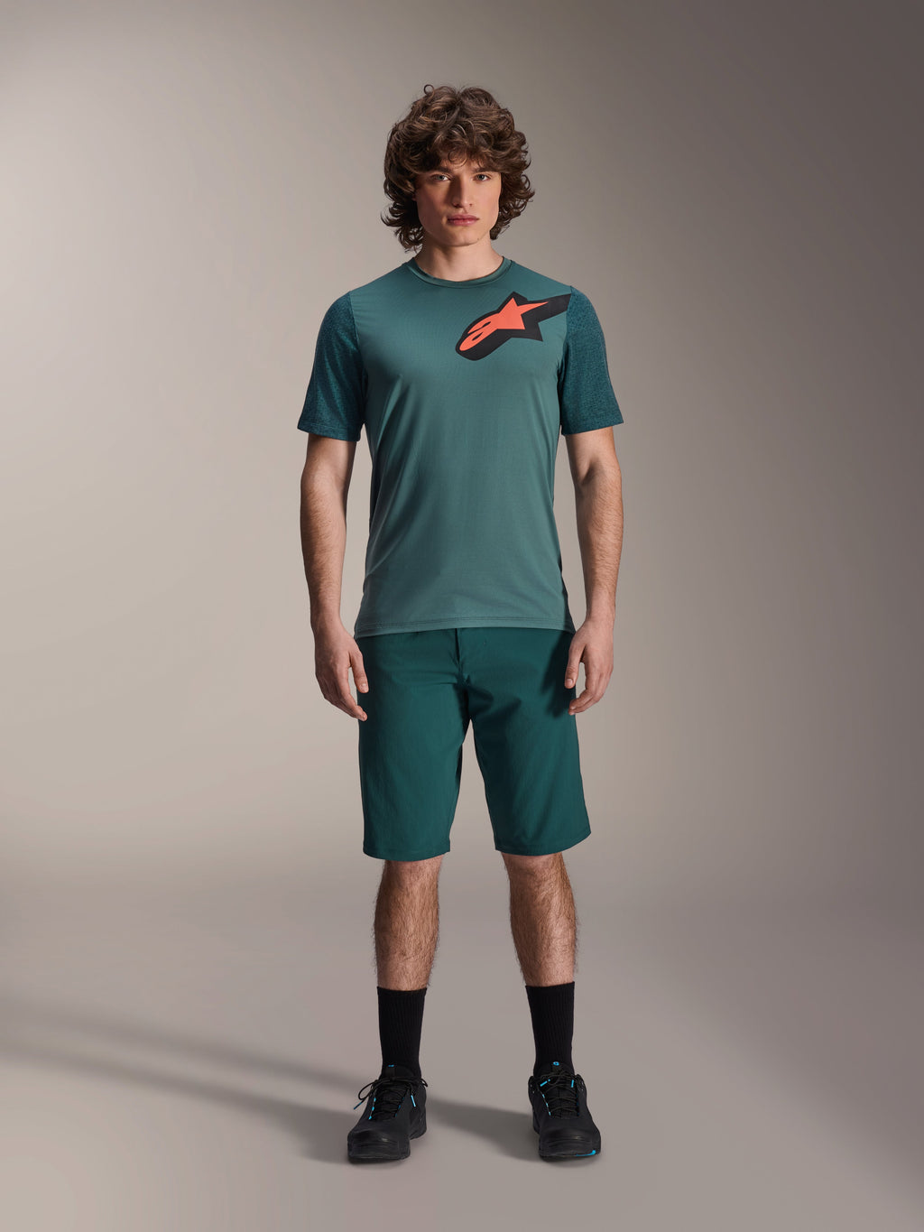 Alpinestars A-Dura Lipan-tröja, kortärmad MTB-tröja, Silver Pine-grön med svart och orange Astars-logotyp på bröstet, kombinerad med matchande shorts och svarta skor, tekniska mountainbike-kläder