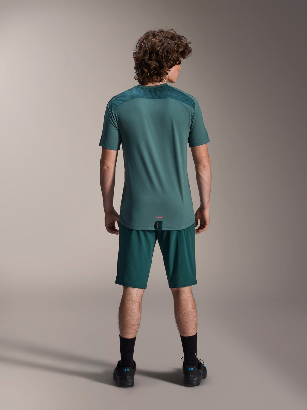 Alpinestars A-Dura shorts och A-Dura Lipan SS jersey, Dark Pine-gröna, vy bakifrån på en modell, prestandakläder för mountainbike bestående av kortärmad jersey och matchande shorts, outfit för terrängcykling