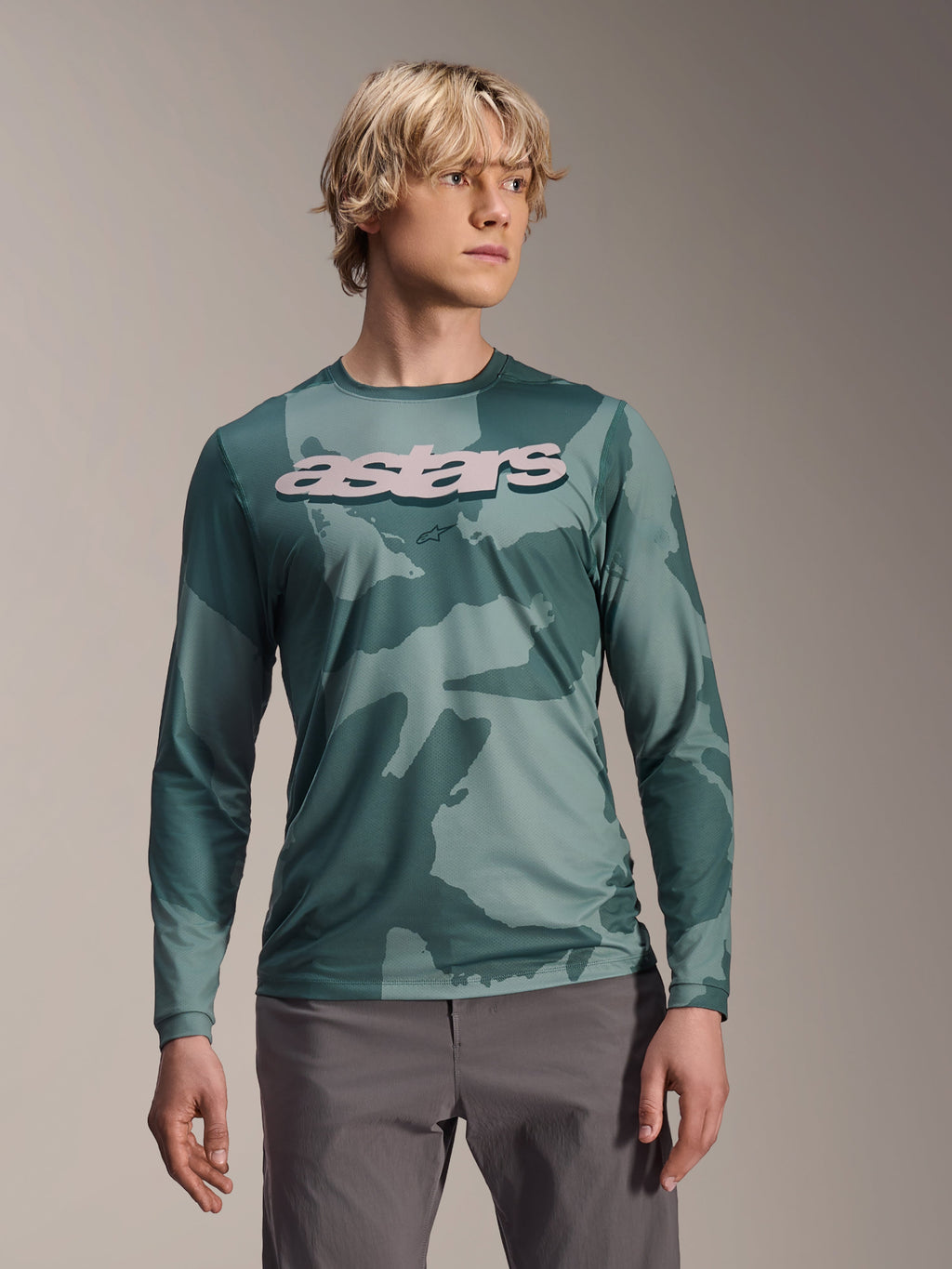 Alpinestars A-Dura Hollow Camo långärmad tröja, MTB-tröja, grönt kamouflagemönster i Silver Pine Camo, stor ljusgrå astars-logotyp på bröstet, bärs med gråa byxor, högpresterande mountainbike-kläder
