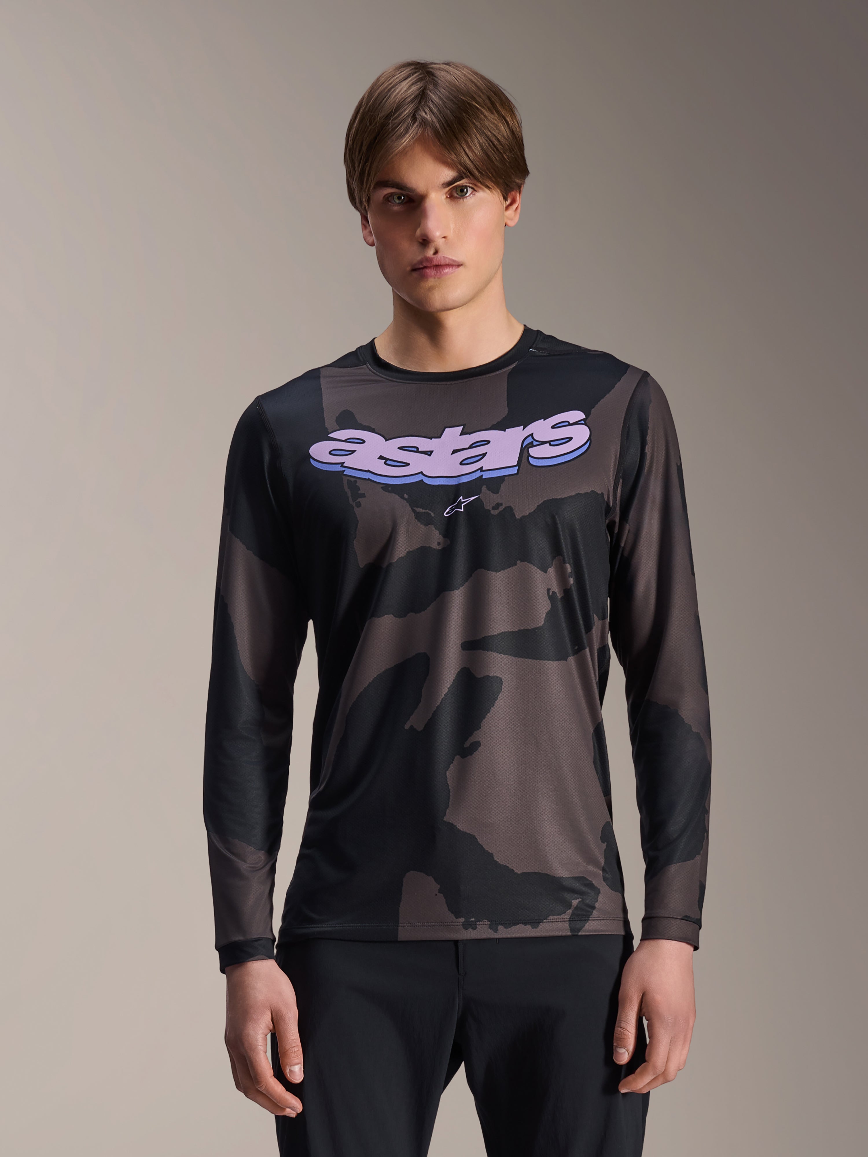 Alpinestars A-Dura Hollow Camo långärmad tröja, MTB-tröja, svart och grått kamouflagemönster, lila 'astars'-grafik på bröstet, bärs av modell med svarta byxor, ledig funktionsdesign