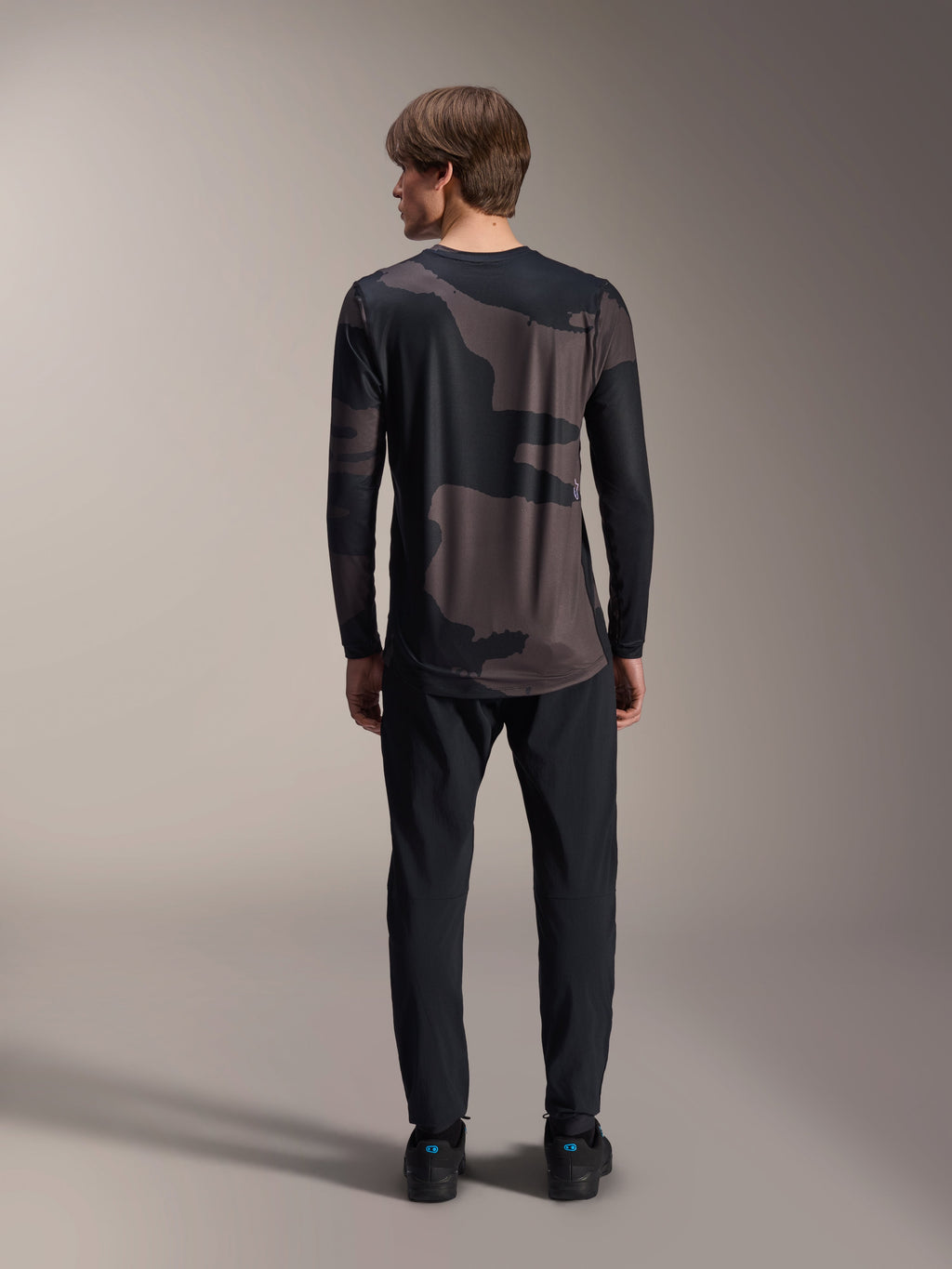 Alpinestars A-Dura Hollow Camo långärmad tröja, Black Camo, baksida buren med svarta byxor, med ett mörkt kamouflagemönster och förlängd rygg för MTB-täckning.