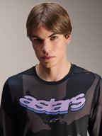 Alpinestars A-Dura Hollow Camo-tröja – långärmad, svart kamouflage med lila 'astars'-grafik på bröstet, studiobild på manlig modell i MTB-kläder, avslappnad och teknisk mountainbikestil