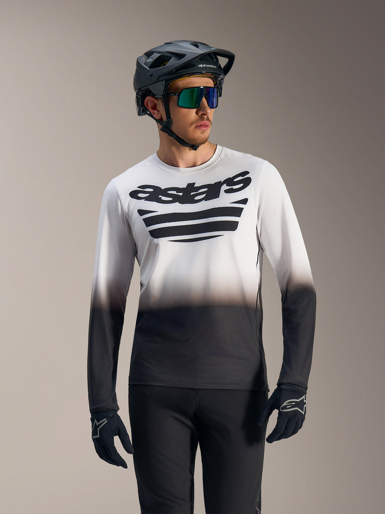 White and black gradient A-Dura ASTARS 2.0 Long Sleeve Jersey with bold chest logo, worn with mountain bike gear.