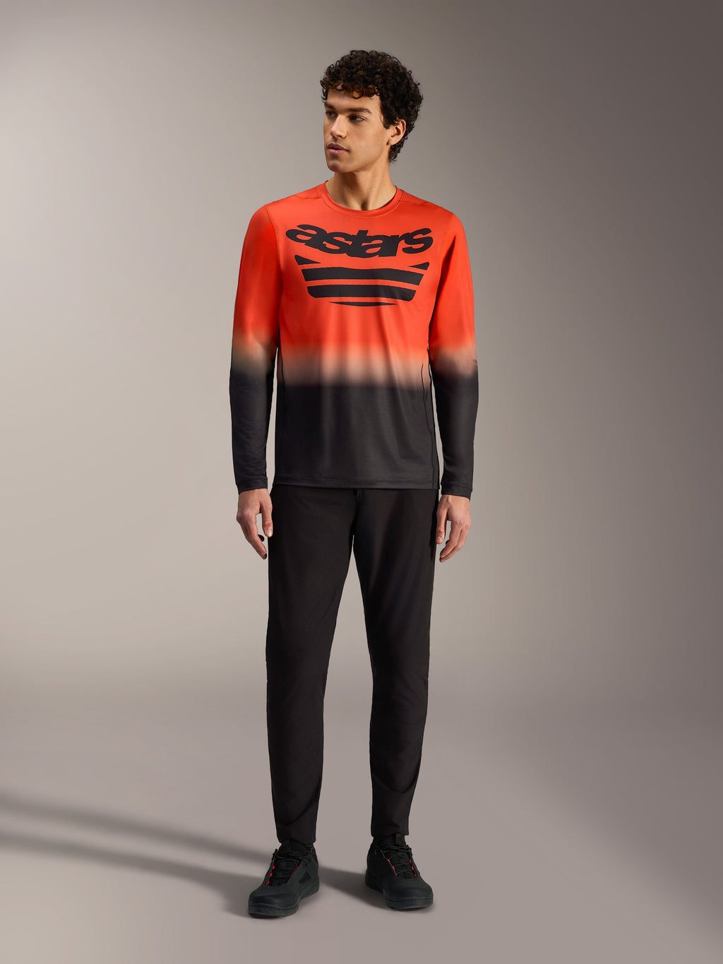 A-Dura ASTARS 2.0 långärmad tröja i orange och svart gradient med stor bröstlogotyp, matchad med svarta MTB-byxor.