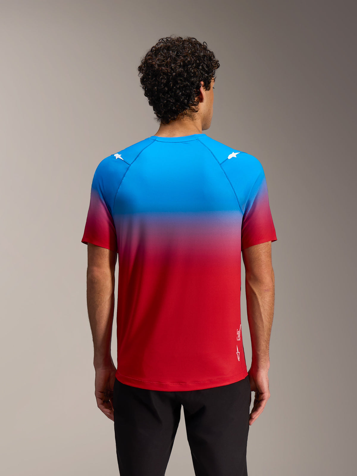 Alpinestars A-Dura ASTARS 2.0 kortärmad tröja i klarröd och blå gradient med stjärnlogotyper på axlarna, baksida.