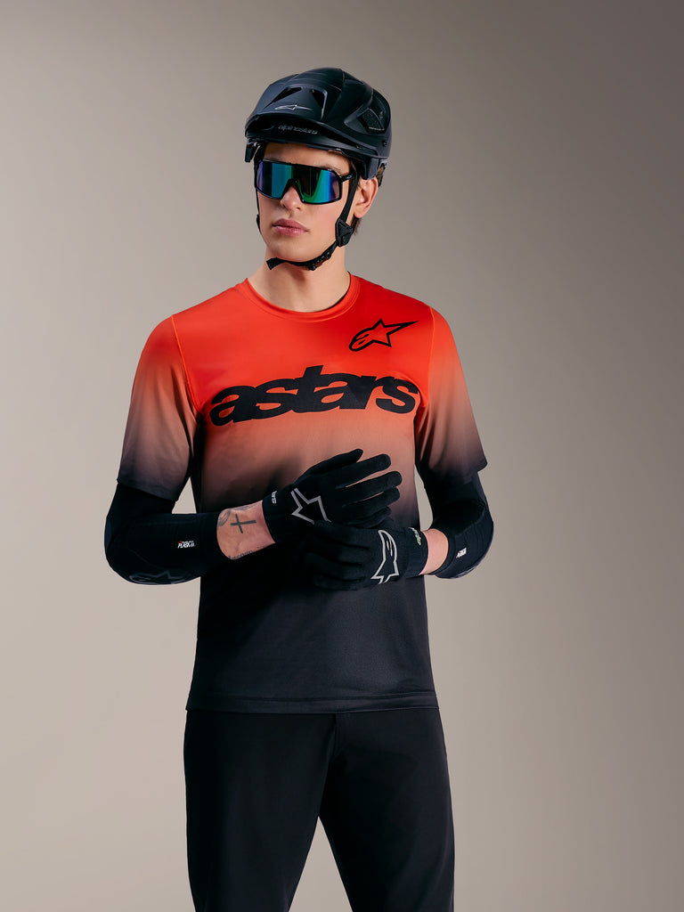 A-Dura ASTARS 2.0, kortärmad MTB-tröja i orange och svart gradient med stor logotyp, förare i svart hjälm och goggles.