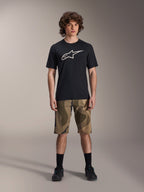 Alpinestars A-Dura Astar kortärmad tröja, svart med stor vit Astars-logotyp på bröstet, bärs av en modell med kamouflagemönstrade MTB-shorts och svarta cykelskor, avslappnade mountainbike-kläder.