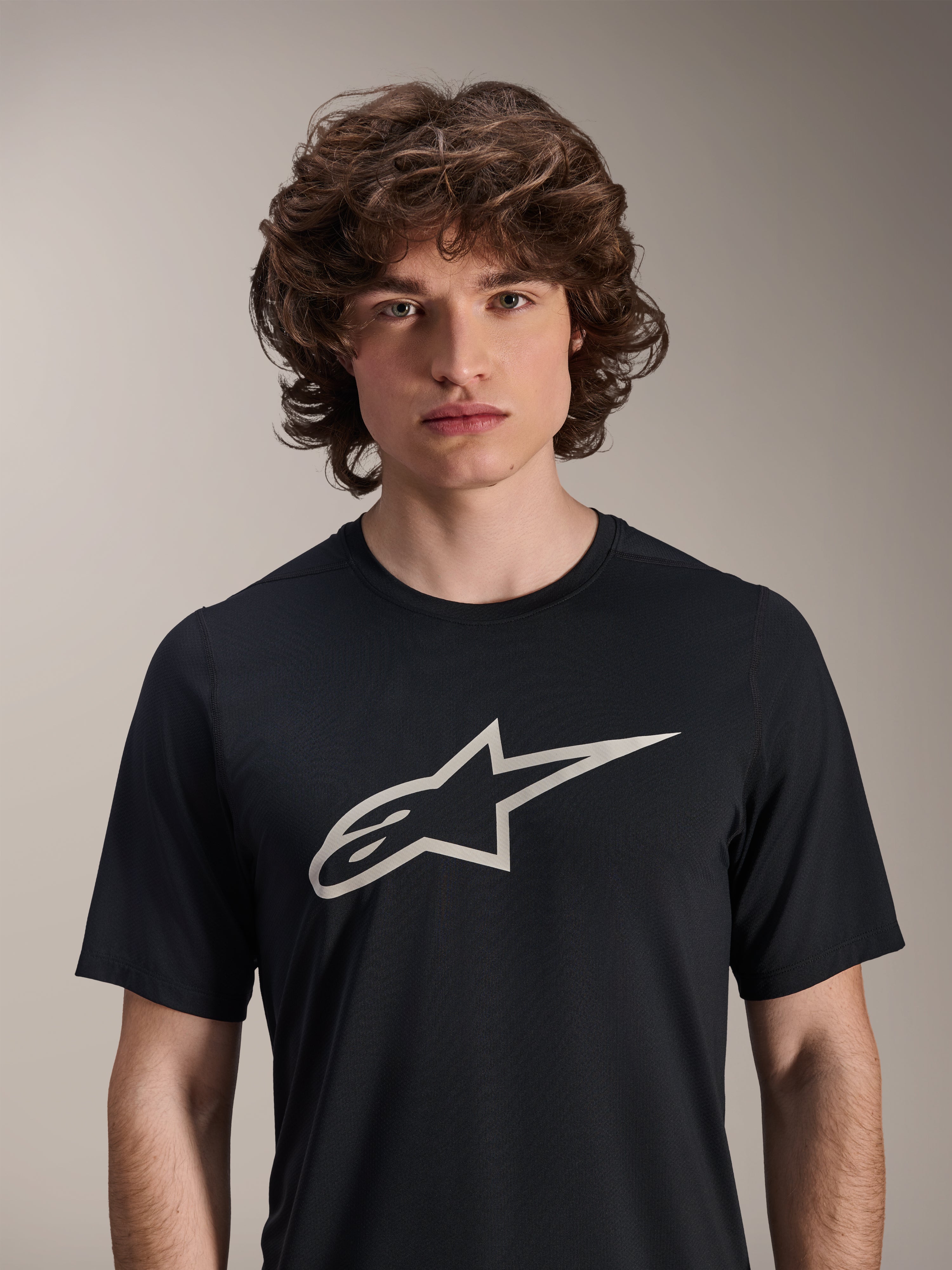 Alpinestars A-Dura Astar kortärmad tröja, svart, med en stor vit Astar-logotyp på bröstet, bärs av en manlig modell, avslappnade funktionskläder för mountainbike