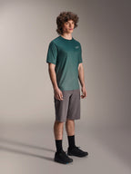 Alpinestars A-Dura Rise Jersey - Short Sleeve i Silver Pine, grön mountainbiketröja bärs av en modell med gråa shorts och svarta sneakers, avslappnad MTB-utrustning för stigcykling med en liten vit logotyp på bröstet