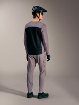 Grå A-Dura Elite 2.0 långärmad MTB-tröja med svart ryggpanel, på modell med matchande cykelutrustning.