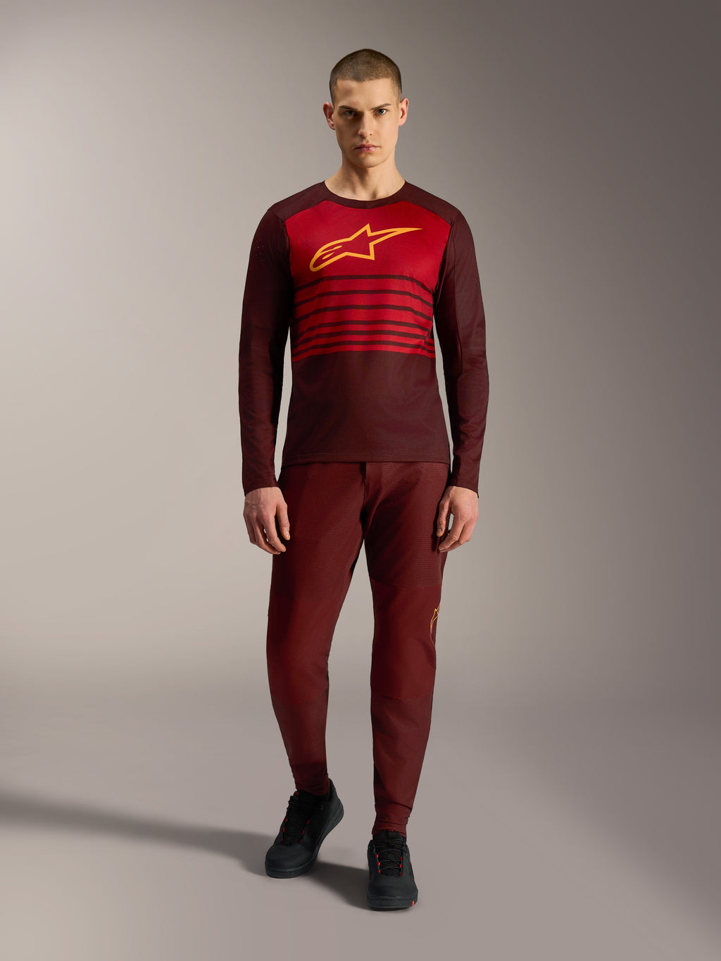 Alpinestars A-Dura Elite 2.0 långärmad tröja i bordeaux med gul bröstlogotyp och röda ränder.