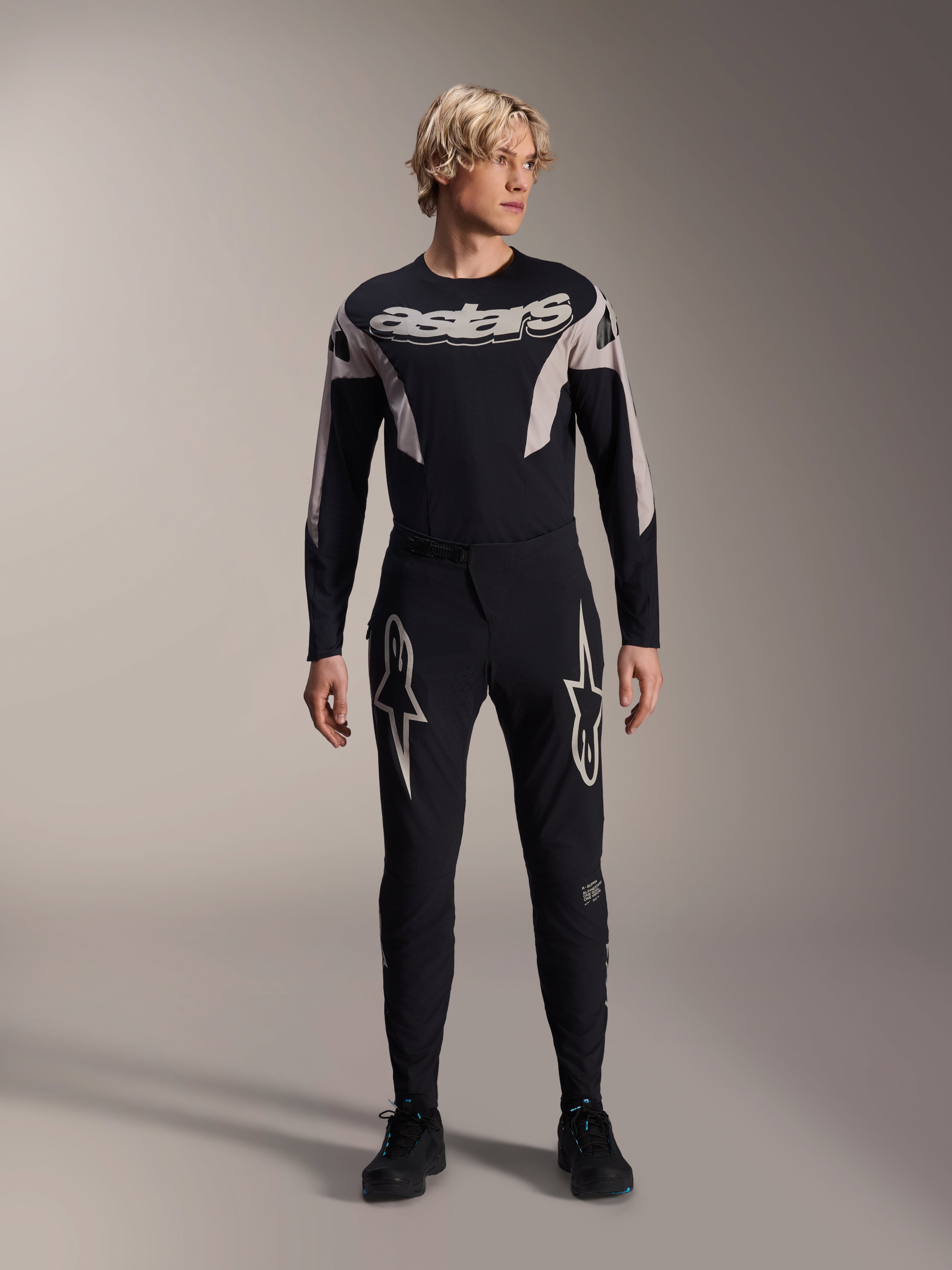 Alpinestars A-Supra Melt-byxor och matchande långärmad tröja, modell som bär ett svart MTB-kit med stora vita stjärngrafiker på låren och 'astars'-logotyp på bröstet, professionella mountainbike-tävlingskläder.