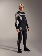 Manlig modell iklädd Alpinestars A-Supra Melt-byxor och matchande långärmad tröja, svart med ljusgrå kurvade mönster, framträdande vita Astars-logotyper på benen och ordmärke på bröstet, professionell MTB-racingoutfit.