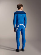 Manlig modell sedd bakifrån i Alpinestars A-Supra Melt långärmad tröja i blått, matchad med matchande blå funktionsbyxor med ett stort vitt Alpinestars-ordmärke över baksidan, komplett MTB-raceställ.