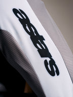 Detalj på A-Supra Elite-tröja i Faded Gray, mikroperforerat tyg med svart ASTARS-logotyp på vitt ärmband.