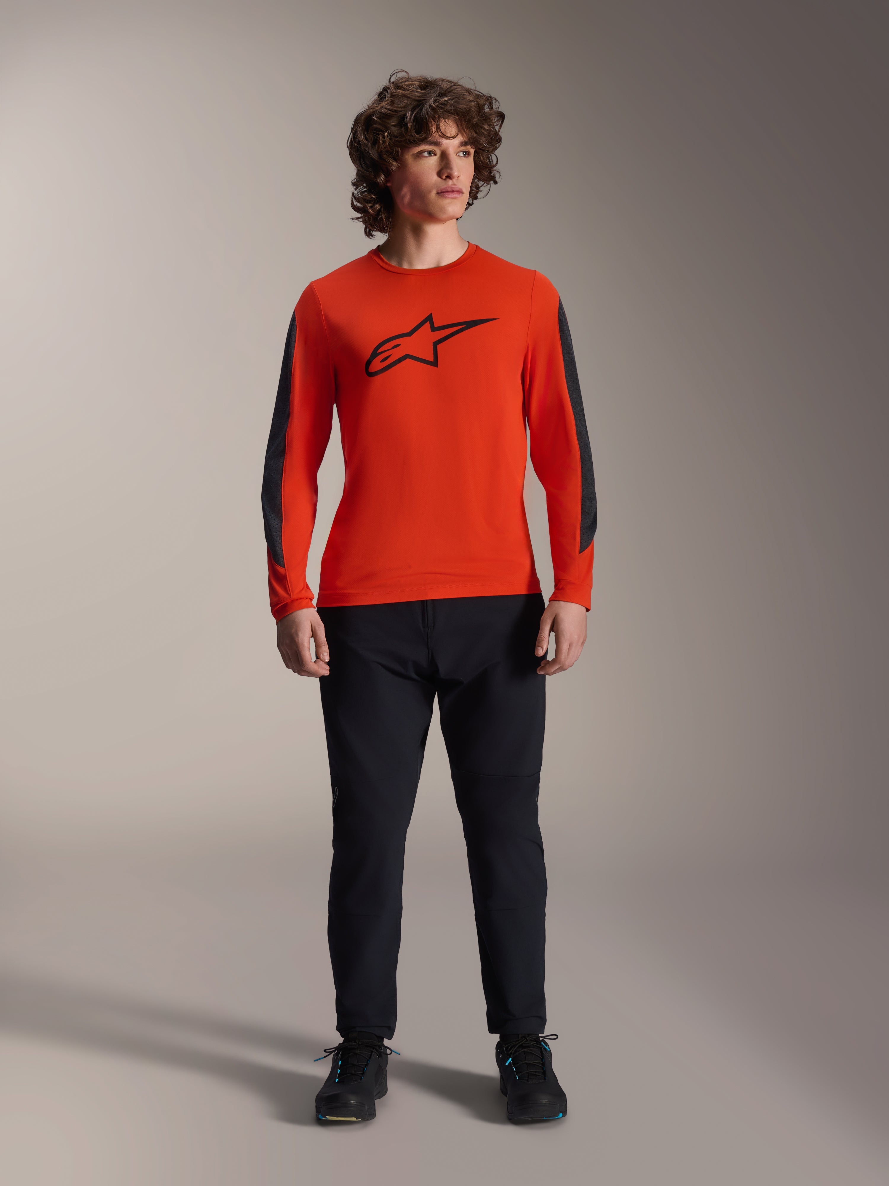 Alpinestars A-Dura Insert Astar-tröja - långärmad, Spicy Orange med svart Astar-logotyp och mörkgrå ärmpaneler, bärs med svarta mountainbike-byxor och skor, hållbar textilkonstruktion för terrängkörning