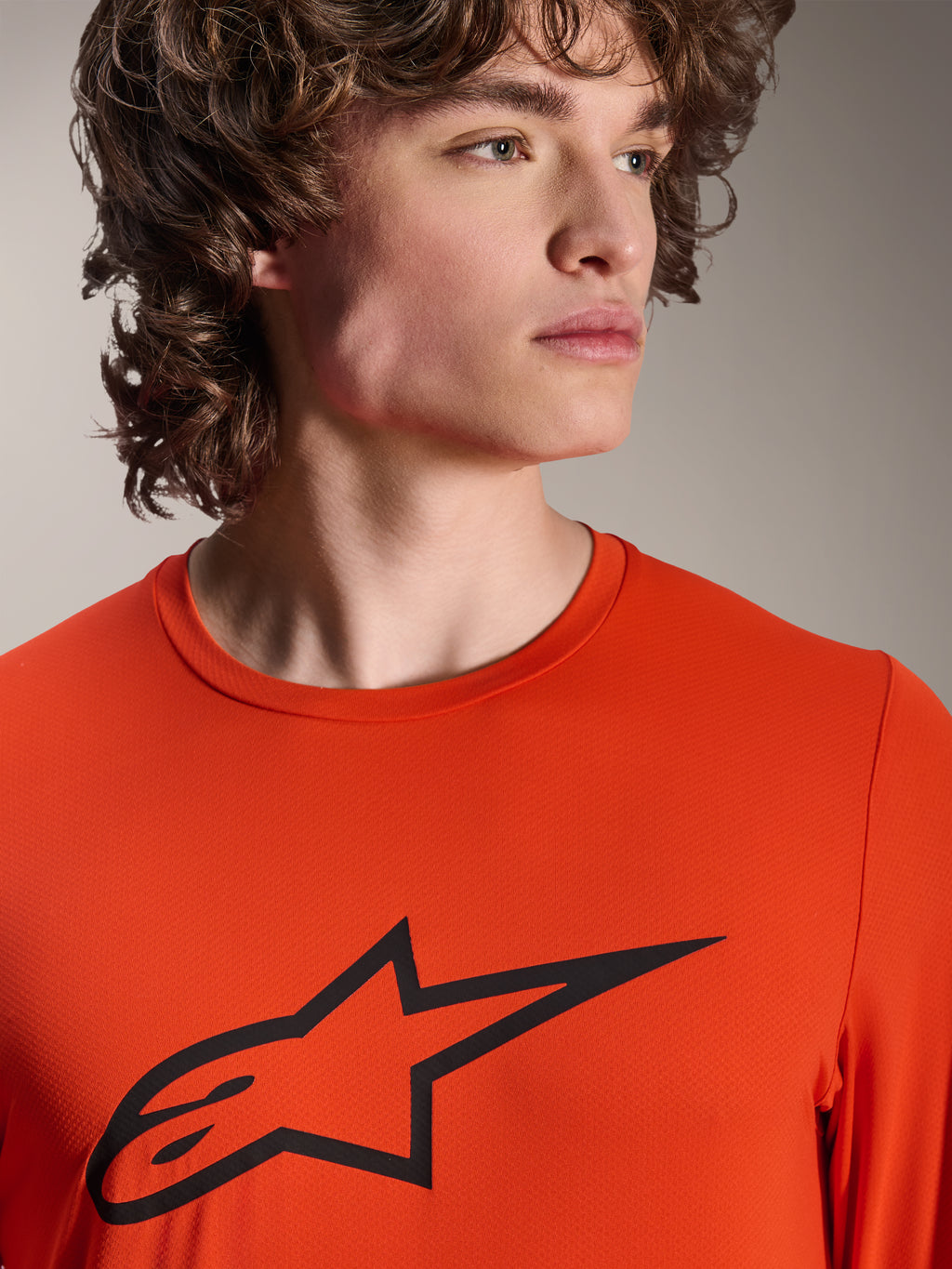 Alpinestars A-Dura Insert Astar-tröja, långärmad MTB-tröja, Spicy Orange, med svart Alpinestars Astar-logotyp på bröstet, närbild på en manlig modell