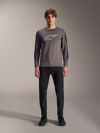Alpinestars A-Dura Insert Astar Jersey, långärmad MTB-tröja, mörkgrå, med en framträdande ljusgrå Astar-logotyp på bröstet och mörkare texturerade ärmpaneler, bärs av en modell med svarta byxor och skor, högpresterande utrustning för mountainbike