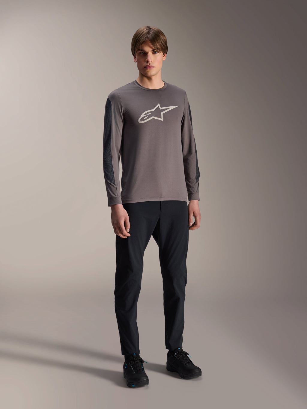 Alpinestars A-Dura Insert Astar Jersey, långärmad MTB-tröja, mörkgrå, med stor vit logotyp på bröstet, bärs med svarta tekniska byxor och svarta skor, cykelkläder för terrängkörning