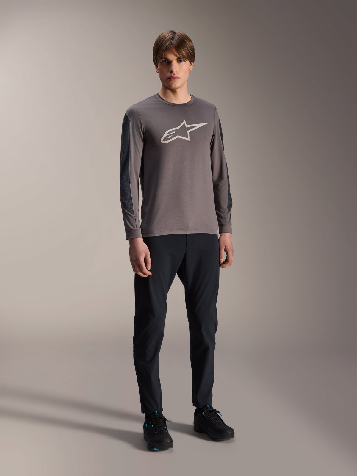 Alpinestars A-Dura Insert Astar Jersey, långärmad MTB-tröja, mörkgrå, med stor vit logotyp på bröstet, bärs med svarta tekniska byxor och svarta skor, cykelkläder för terrängkörning