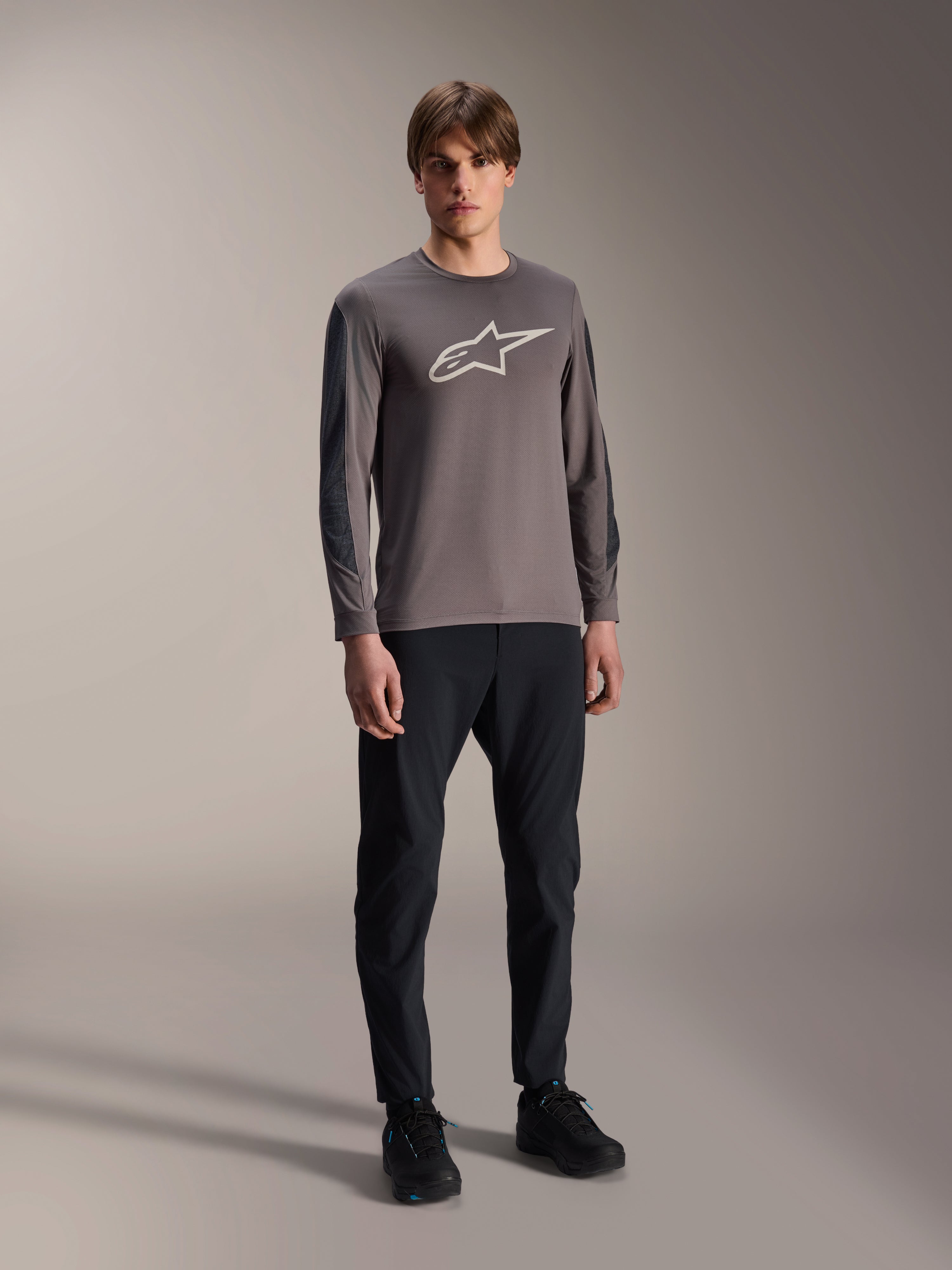 Alpinestars A-Dura Insert Astar Jersey, långärmad MTB-tröja, mörkgrå, med stor vit logotyp på bröstet, bärs med svarta tekniska byxor och svarta skor, cykelkläder för terrängkörning