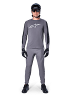Alpinestars A-Dura Dri Astar-tröja, långärmad MTB-tröja i mörkgrått, med vit logotyp på bröstet och svarta paneler på ärmarna, bärs med matchande grå byxor, svart hjälm, solglasögon och handskar för en komplett outfit för terrängcykling