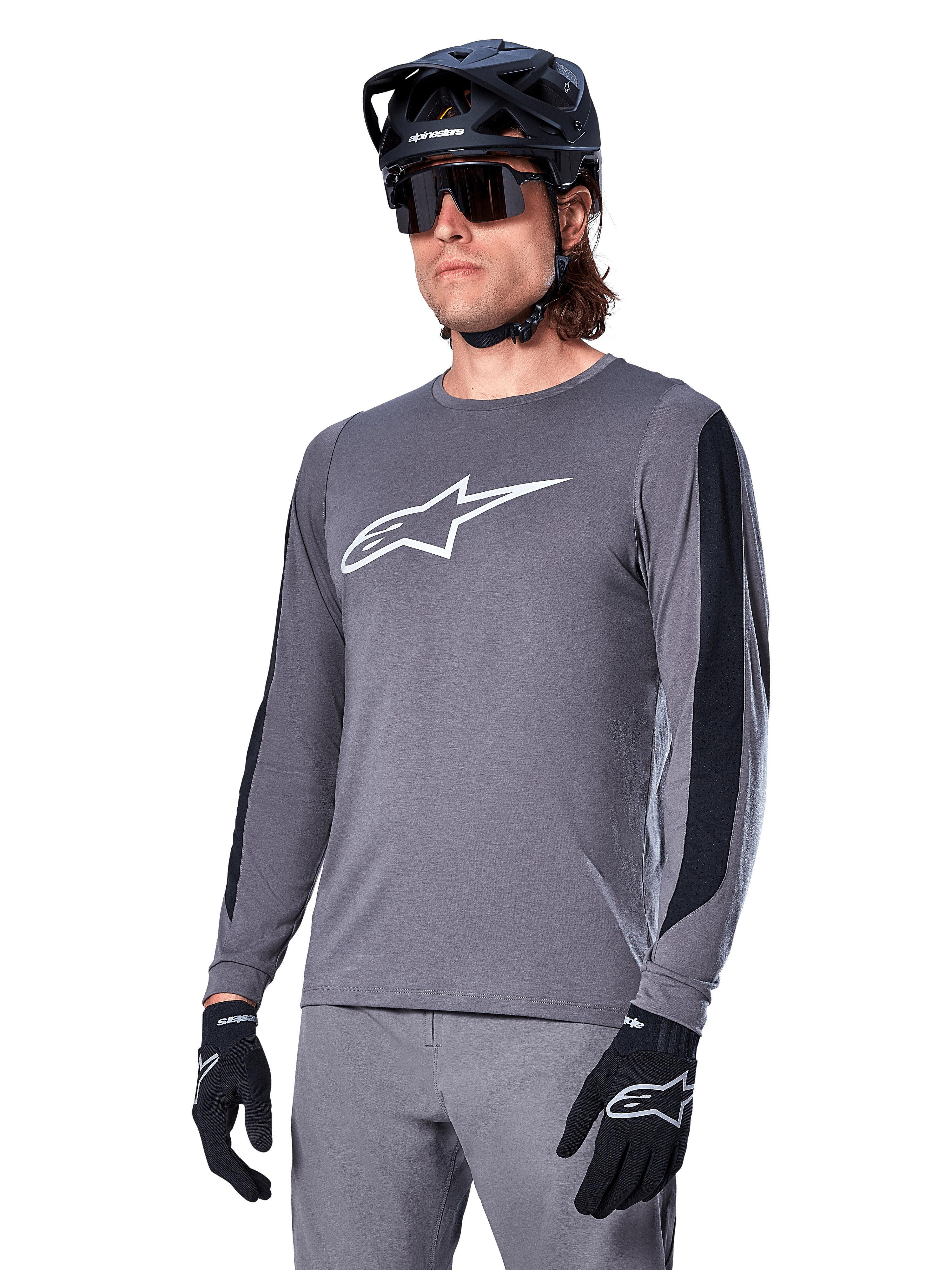Alpinestars A-Dura Dri Astar långärmad tröja, mörkgrå med vit logotyp på bröstet och svarta meshpaneler på sidorna, MTB-cykeltröja, bärs med svart hjälm, solglasögon och matchande grå byxor