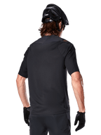 Alpinestars A-Aria Polartec Switch Short Sleeve Jersey, Black, rear view on a rider wearing a black mountain bike helmet, matching black shorts and gloves, performance gear for mountain biking
