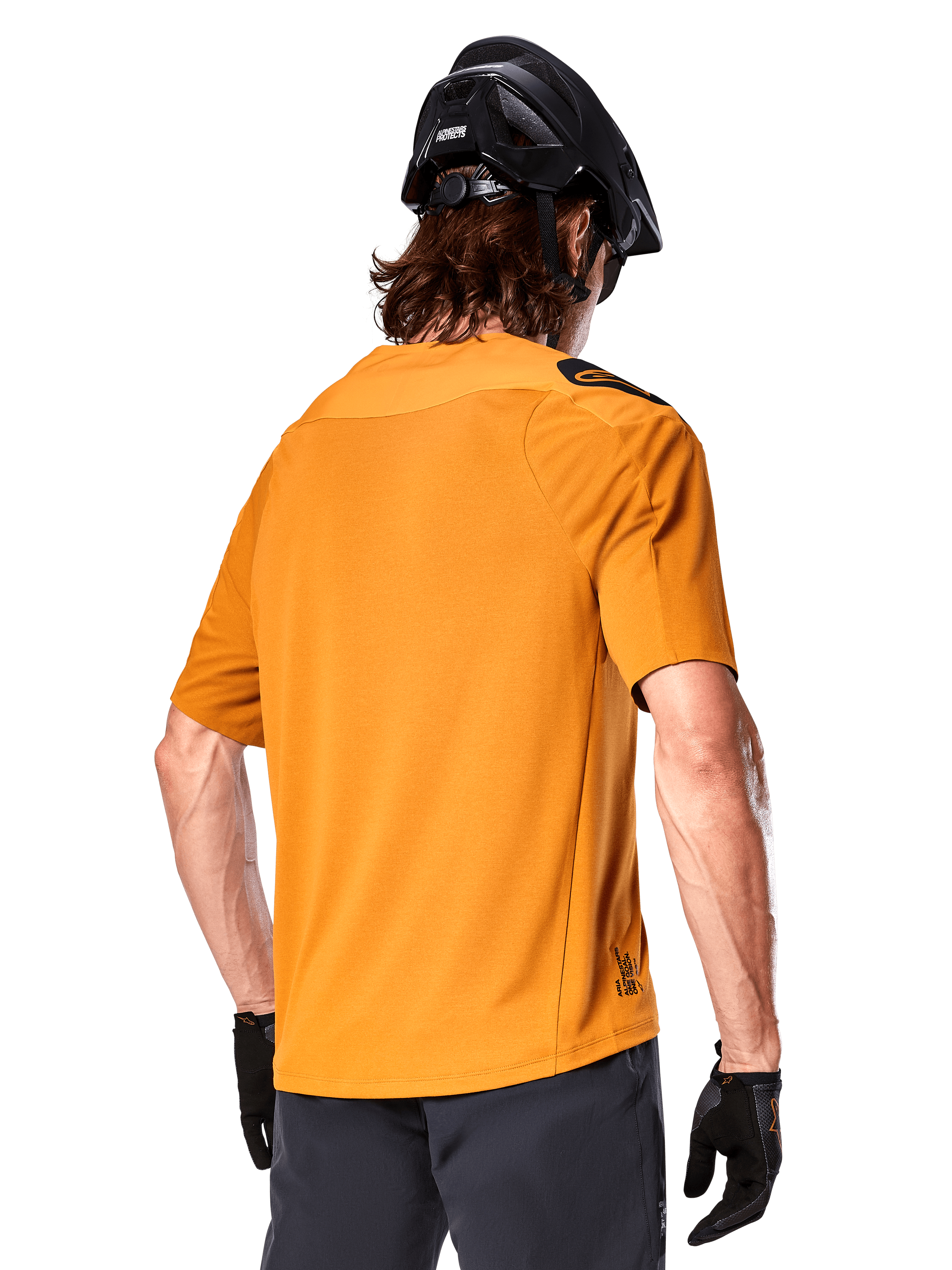 Alpinestars A-Aria Polartec Switch tröja, kortärmad MTB-tröja, Dark Gold, vy bakifrån som visar prestandapassform, bärs med svart hjälm och gråa shorts, slitstarka och ventilerande kläder för stigcykling