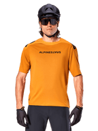 Alpinestars A-Aria Polartec Switch kortärmad tröja, Dark Gold, mountainbike-cyklist som bär svart hjälm och solglasögon, högpresterande cykelkläder för MTB-stigar