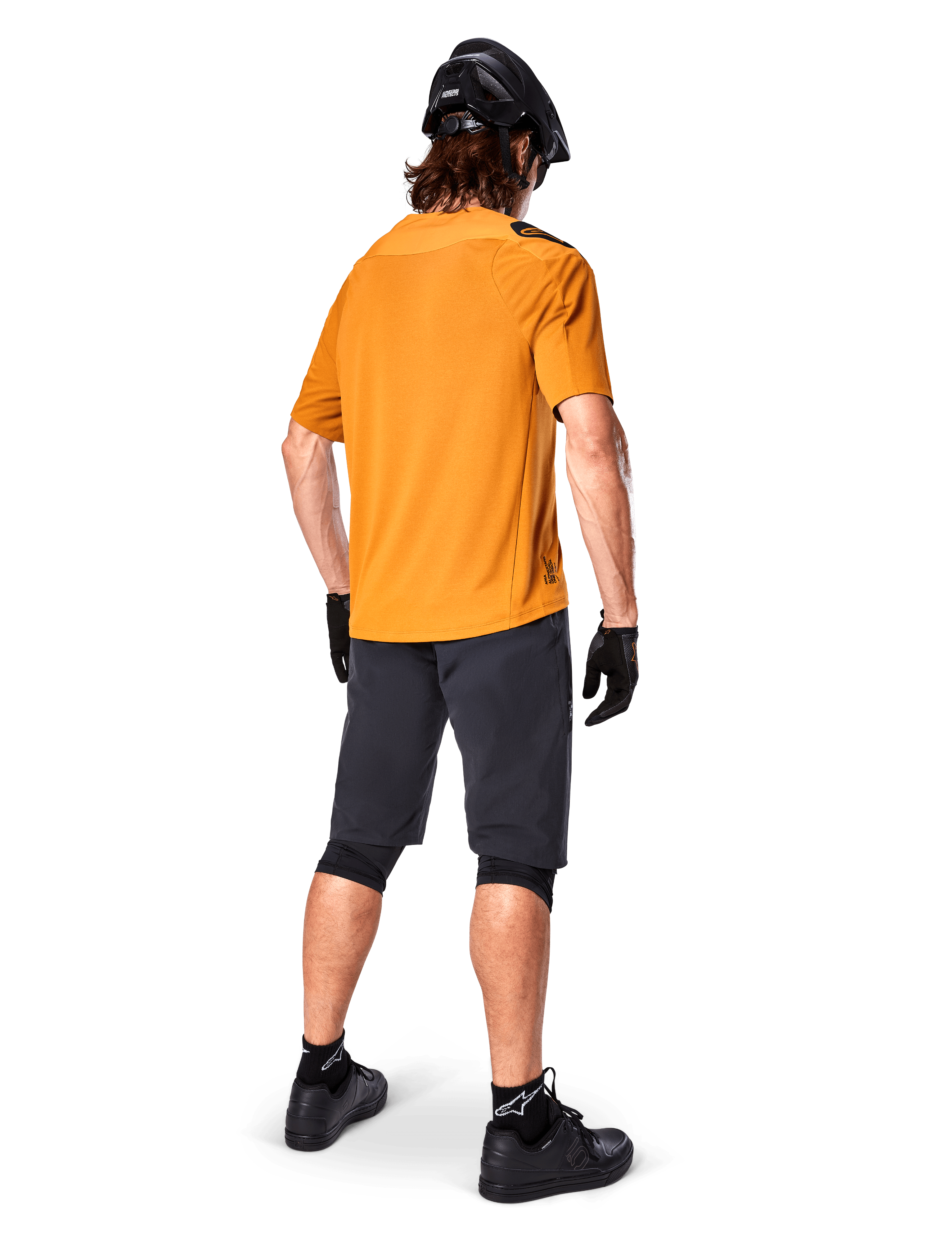 Alpinestars A-Aria Polartec Switch-tröja, kortärmad MTB-tröja, mörkt guld, baksida av modell som bär mörkgrå mountainbike-shorts, svart hjälm och handskar, tekniska cykelkläder för terrängstigar