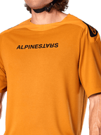 Alpinestars A-Aria Polartec Switch tröja, kortärmad MTB-tröja, mörkt guld, med spegelvänd svart Alpinestars-logotyp på bröstet, tekniskt funktionsmaterial för mountainbike-cykling på stigar