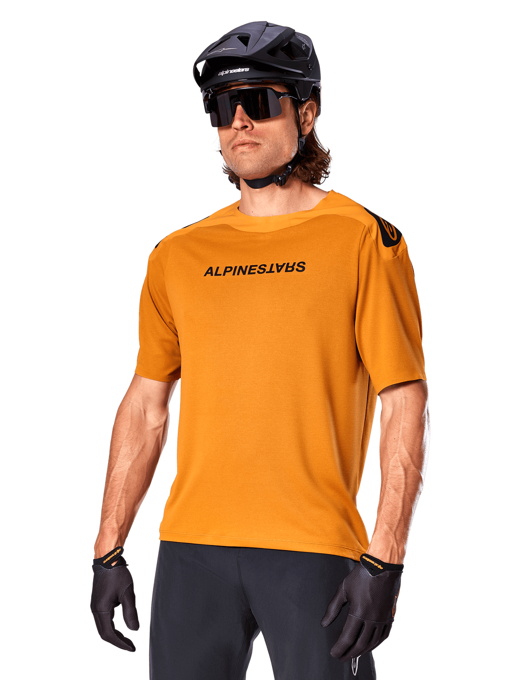 Alpinestars A-Aria Polartec Switch Jersey, kortärmad MTB-tröja, Dark Gold med svart logotyp, bärs av modell med svart hjälm, solglasögon och cykelhandskar, högpresterande mountainbike-kläder