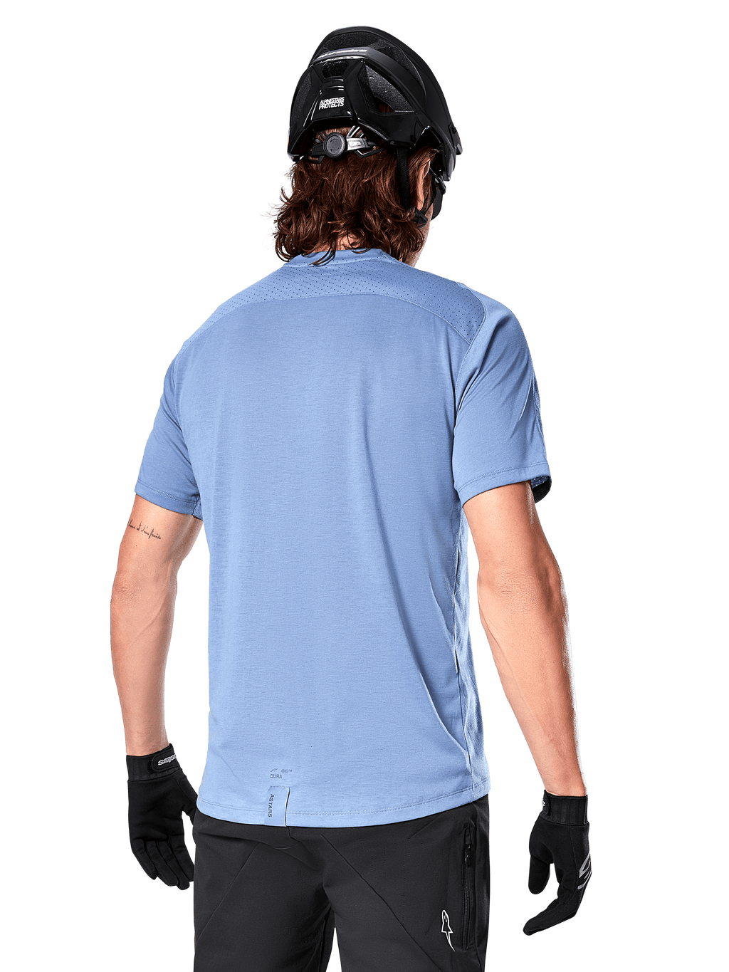 Alpinestars A-Dura Dri Astar kortärmad tröja, MTB-tröja, Infinity Blue, baksida som visar nätpaneler för ventilation på axlarna och en förlängd rygg, bärs med en svart MTB-hjälm och handskar, prestanda-cykelutrustning