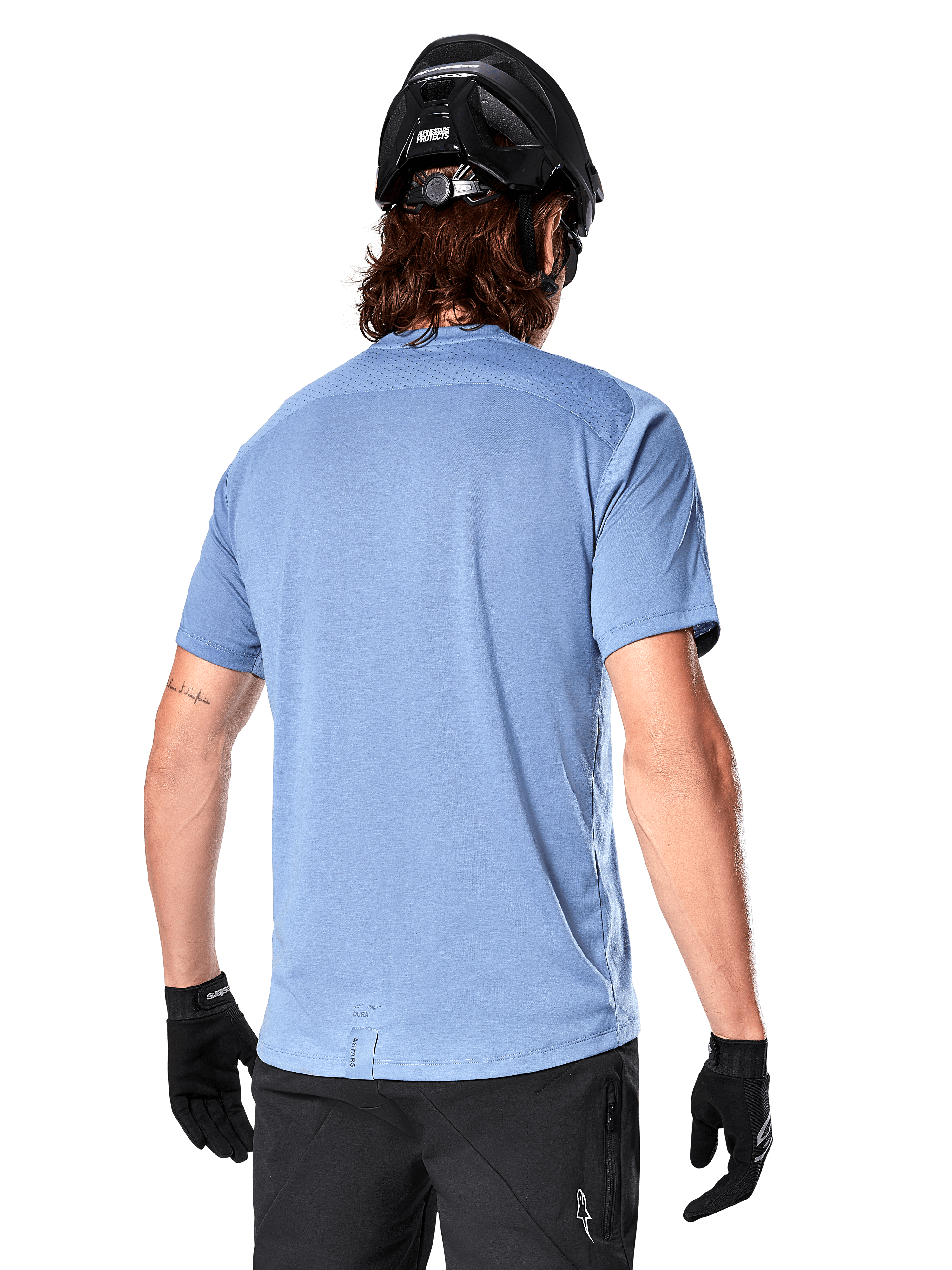 Alpinestars A-Dura Dri Astar kortärmad tröja, MTB-tröja, Infinity Blue, baksida som visar nätpaneler för ventilation på axlarna och en förlängd rygg, bärs med en svart MTB-hjälm och handskar, prestanda-cykelutrustning