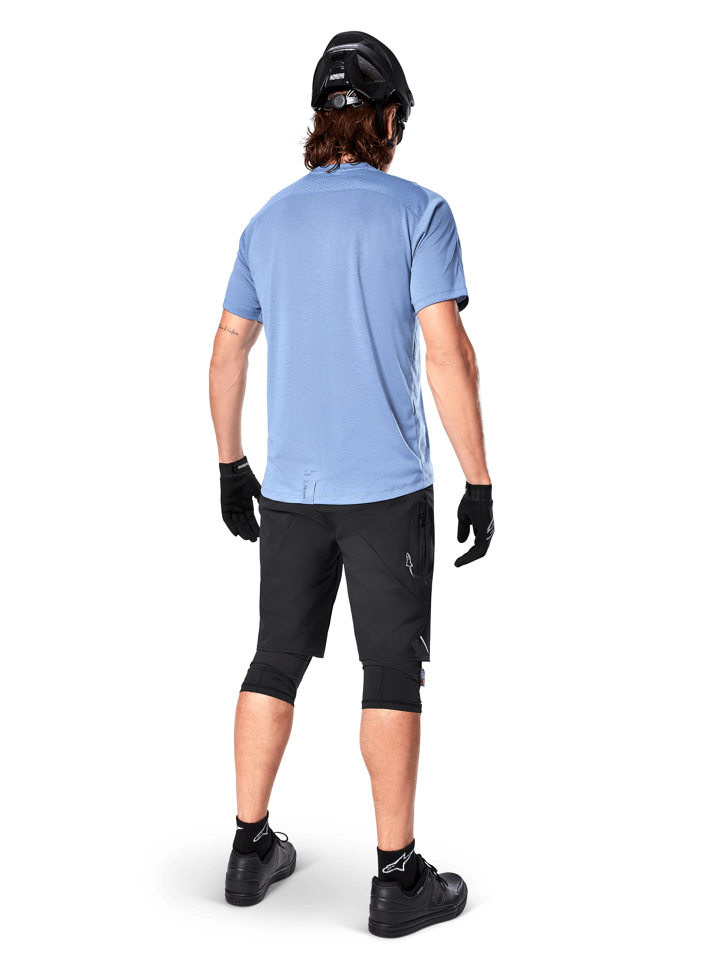 Alpinestars A-Dura Dri Astar kortärmad tröja, Infinity Blue, vy bakifrån, matchad med svarta mountainbikeshorts och hjälm, tekniska cykelkläder med fukttransporterande material och förlängd rygg