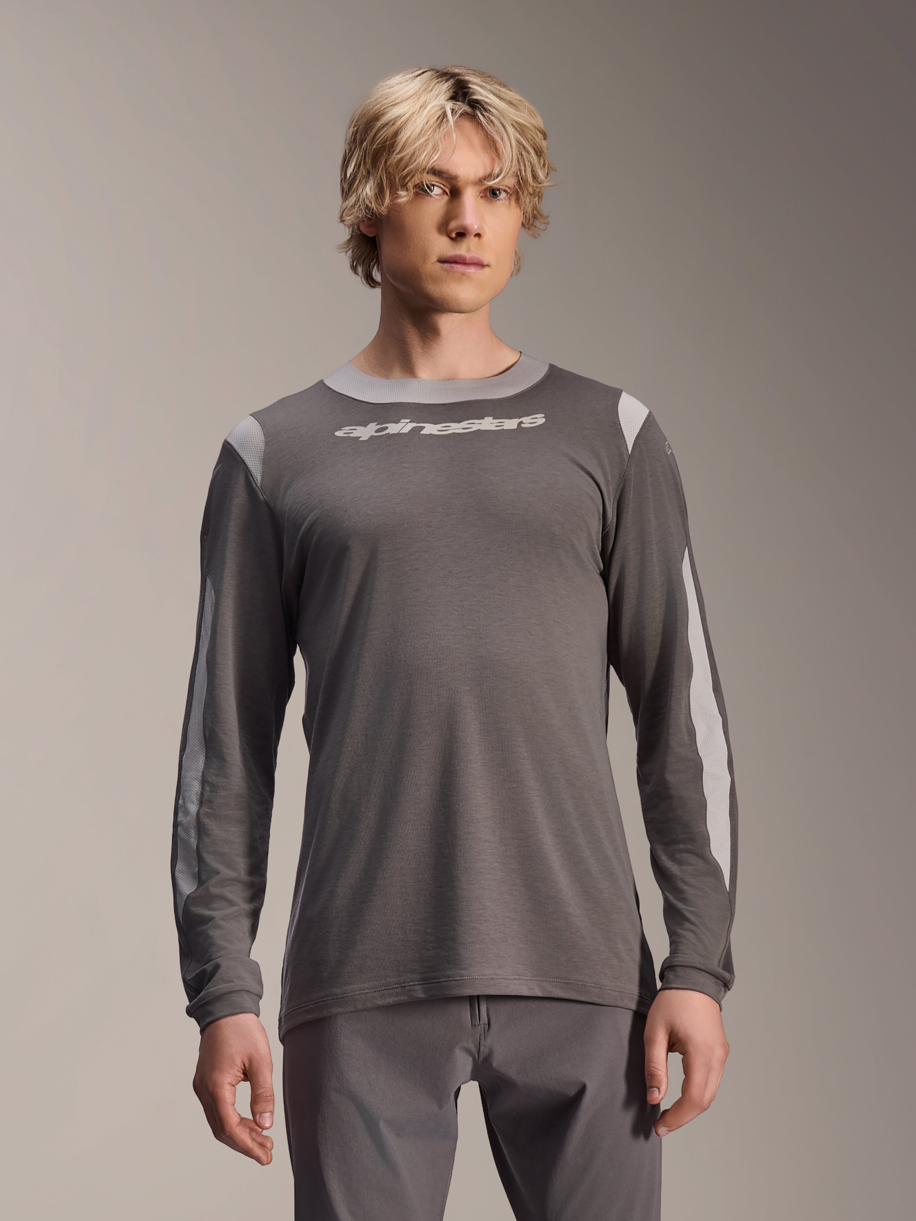 Alpinestars A-Dura Dri Wool Jersey långärmad tröja, mörkgrå, bärs av manlig modell, med ljusgrå meshpaneler på axlar och ärmar, vit logotyp på bröstet, högpresterande mountainbikeutrustning