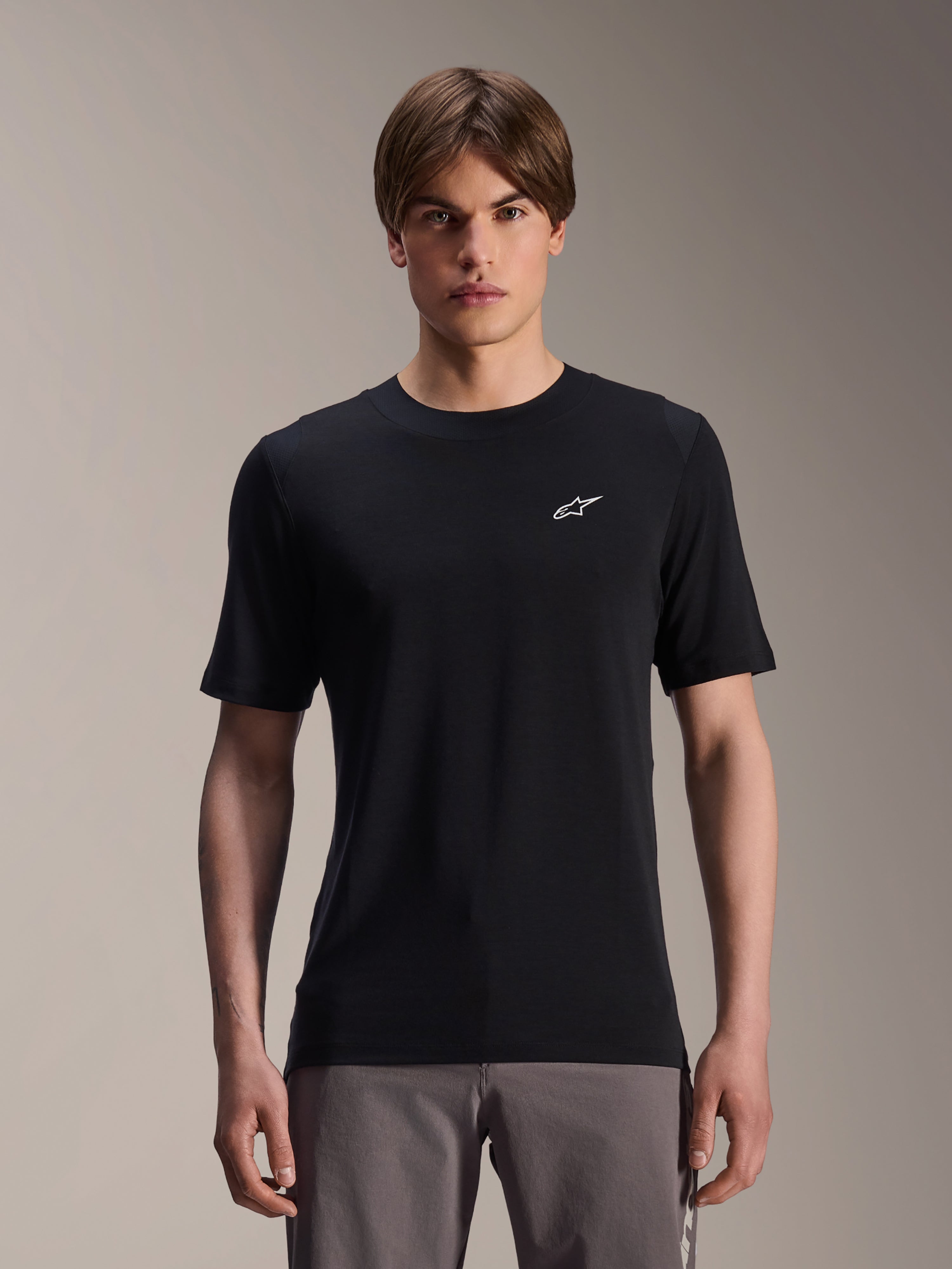 Alpinestars A-Dura Dri Wool kortärmad tröja, svart, bärs av manlig modell, liten vit Alpinestars-logotyp på bröstet, funktionella cykelkläder för MTB-trailcykling, fukttransporterande drirelease-ullmaterial