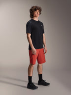 Manlig modell iklädd Alpinestars A-Dura Elite-shorts i Dark Orange och A-Dura Dri Wool kortärmad tröja i svart, prestationskläder för mountainbike, kombinerat med svarta strumpor och skor, atletisk design för terrängcykling.