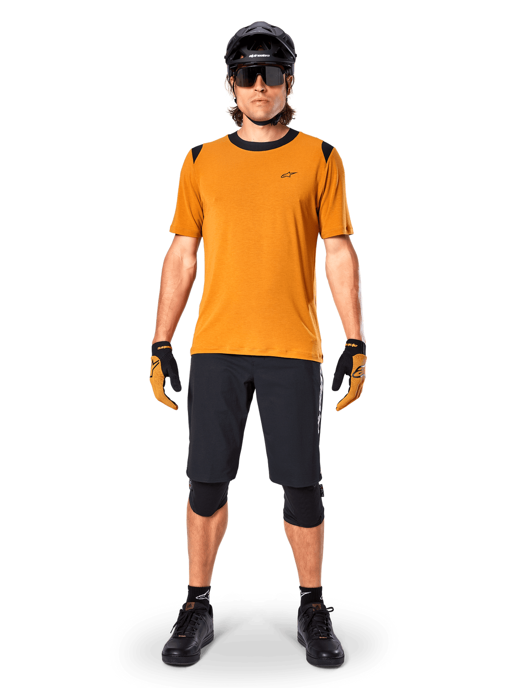 Alpinestars A-Dura Dri Wool Short Sleeve Jersey in Dark Gold, mountain bike jersey worn with black shorts and protective gear, mustard yellow fabric with black collar and shoulder accents, performance cycling apparel for trail riding.