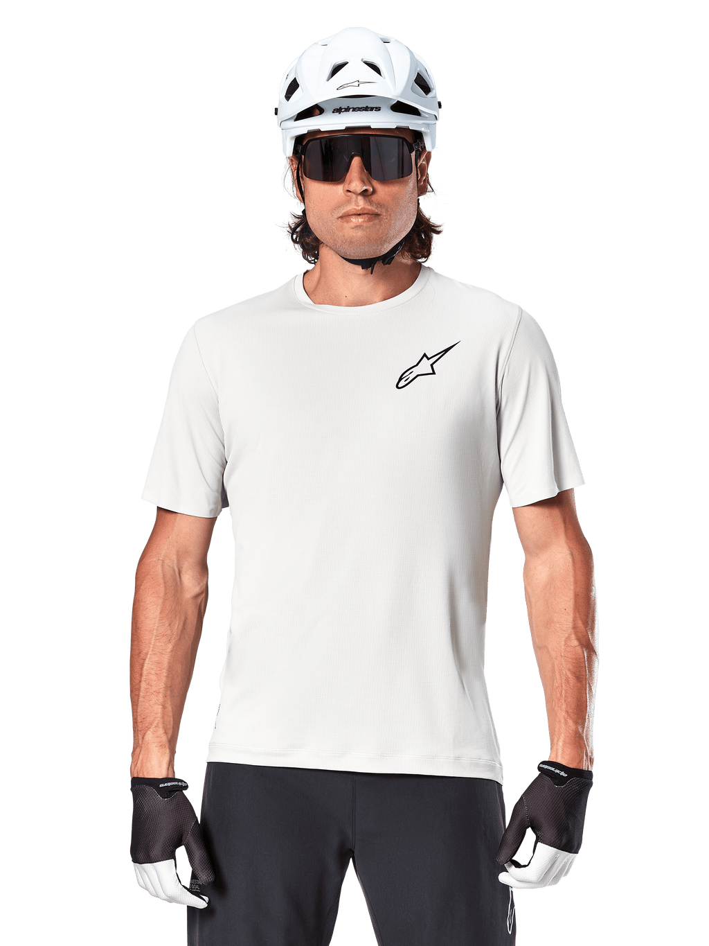 Cyklist som bär Alpinestars A-Aria Astar kortärmad tröja, White Dove med liten svart Astar-logotyp på bröstet, vit cykelhjälm, svarta solglasögon och svartvita handskar, prestanda-MTB-utrustning för terrängkörning