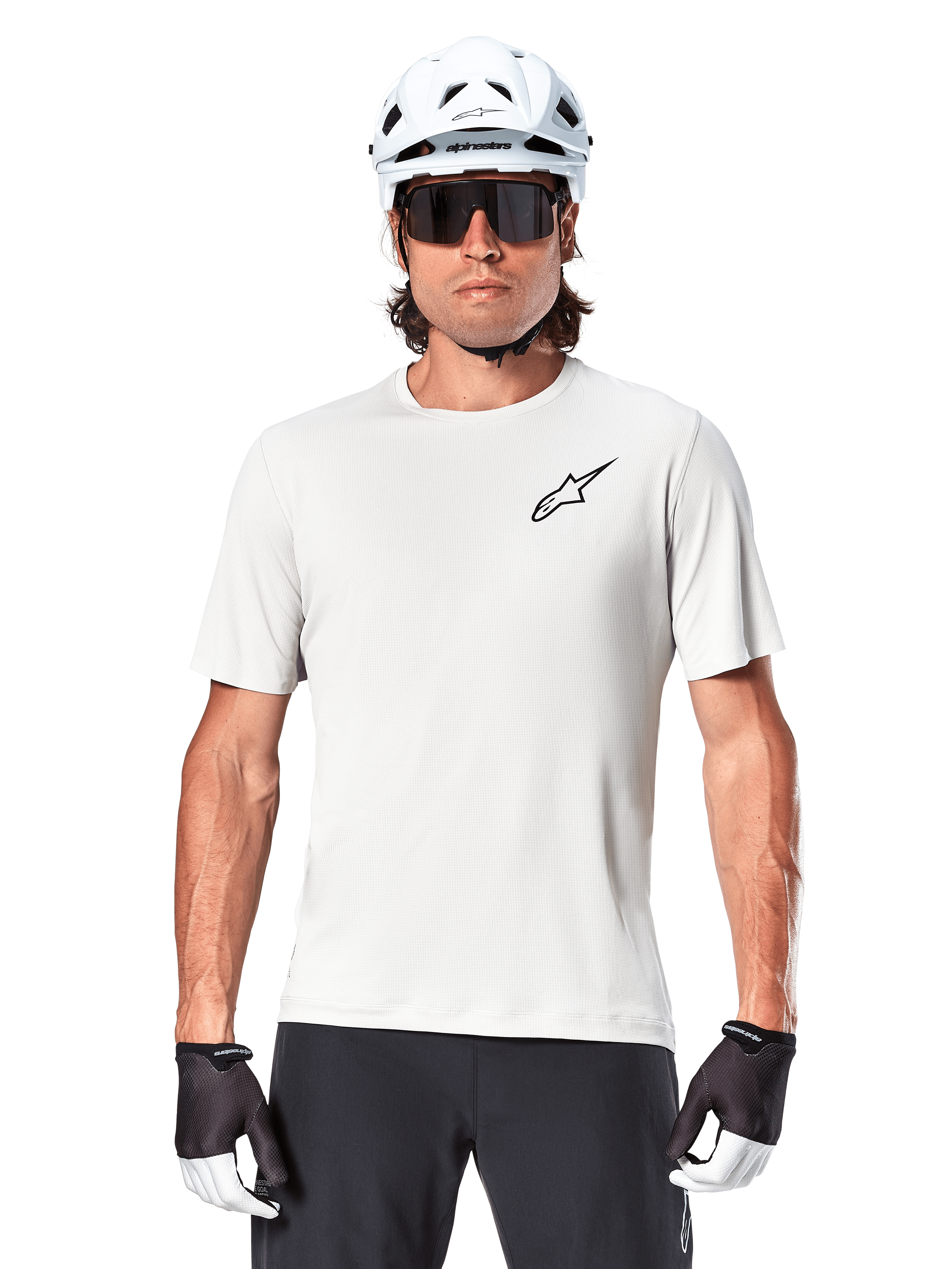 Cyklist som bär Alpinestars A-Aria Astar kortärmad tröja, White Dove med liten svart Astar-logotyp på bröstet, vit cykelhjälm, svarta solglasögon och svartvita handskar, prestanda-MTB-utrustning för terrängkörning