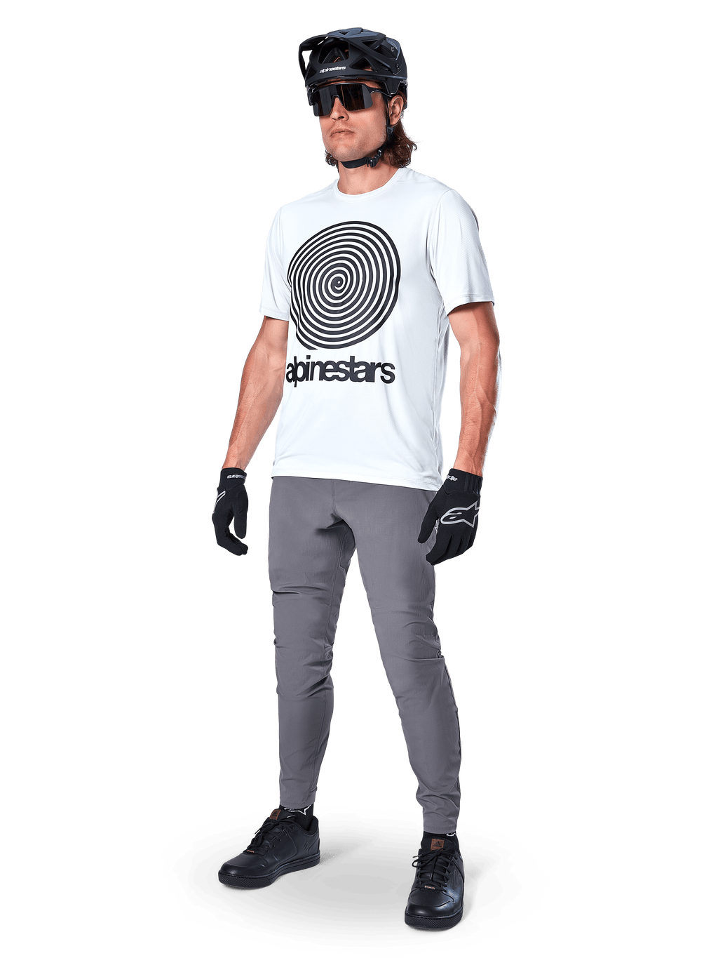 Alpinestars A-Dura Oscar tröja – kortärmad, White Dove med stor svart spiralgrafik, bärs av en cyklist med gråa MTB-byxor, svart hjälm och handskar, högpresterande cykelkläder för terrängkörning