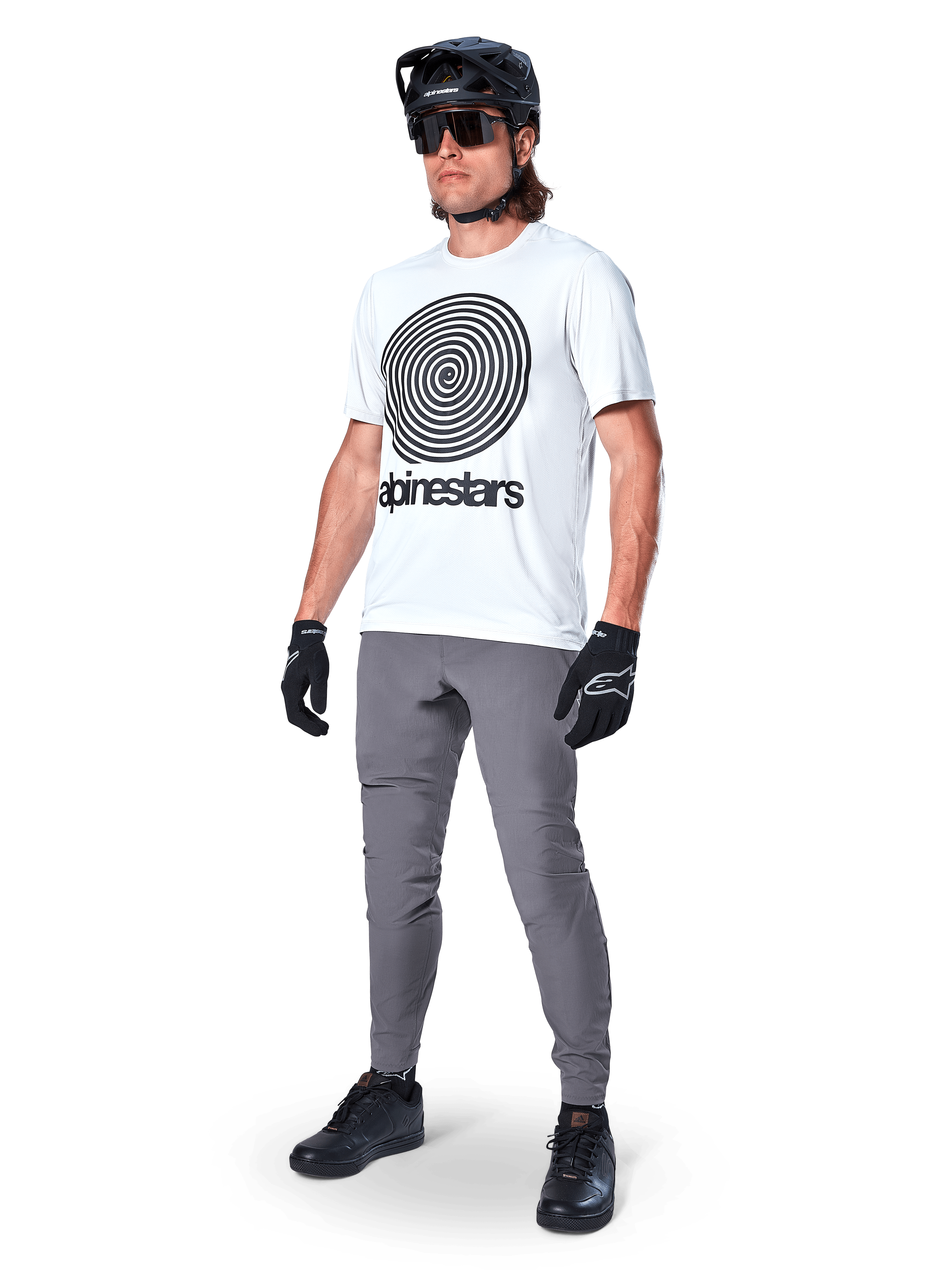 Alpinestars A-Dura Oscar tröja – kortärmad, White Dove med stor svart spiralgrafik, bärs av en cyklist med gråa MTB-byxor, svart hjälm och handskar, högpresterande cykelkläder för terrängkörning