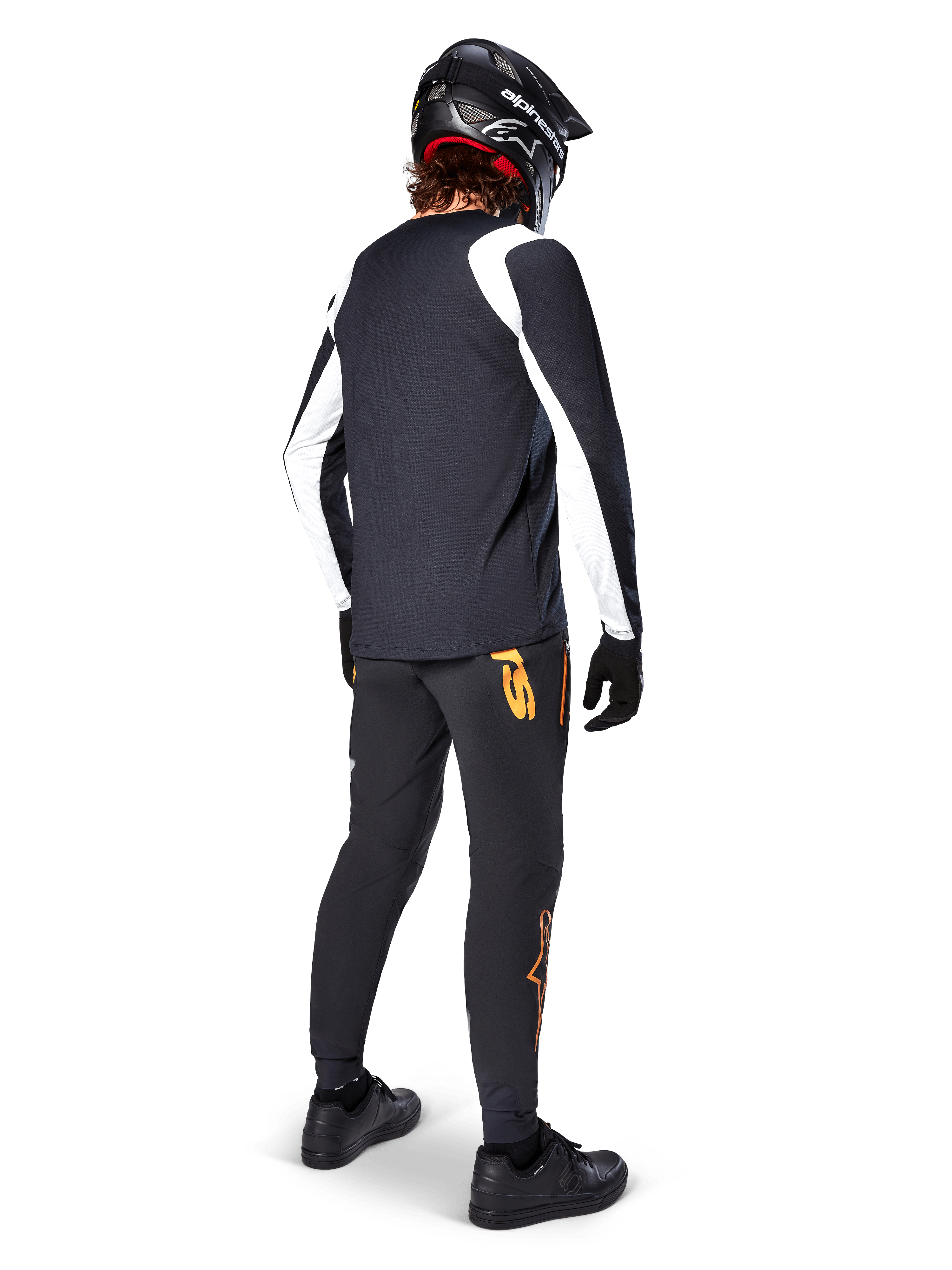 Alpinestars A-Supra Oscar Long Sleeve Jersey, Black with white panels on sleeves, worn by an MTB rider from the back with a black full-face helmet and black pants featuring orange logos, cycling apparel for off-road gravity riding