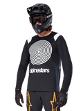 Alpinestars A-Supra Oscar Long Sleeve Jersey, MTB Cycling Jersey, Black and White, featuring a bold white spiral design and Alpinestars logo on the chest, worn with a black full-face helmet and goggles, performance mountain biking apparel