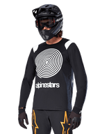 Alpinestars A-Supra Oscar Long Sleeve Jersey, MTB Cycling Jersey, Black and White, featuring a bold white spiral design and Alpinestars logo on the chest, worn with a black full-face helmet and goggles, performance mountain biking apparel