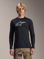 Alpinestars A-Dura Astar långärmad tröja, svart med silverfärgad Astars-logotyp på bröstet, bärs av en modell med kamouflagebyxor, avslappnade MTB-funktionskläder för mountainbike