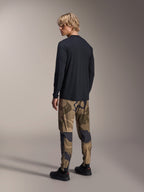 Alpinestars A-Dura Camo Pant, MTB-byxor, brunt kamouflage, bärs med en svart långärmad tröja och svarta sneakers, vy bakifrån som visar avsmalnande ben och elastiska muddar, funktionskläder för terrängcykling